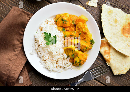 Leckere Chicken Curry mit Reis auf Holz- Hintergrund. Ansicht von oben, flach Stockfoto