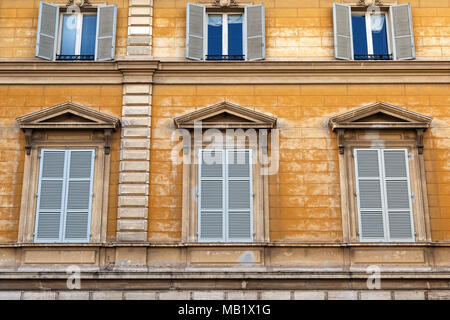 Blaue Fensterläden und verwitterten gelb gestrichenen Wänden auf einem Gebäude in der Stadt Rom, Italien. Stockfoto