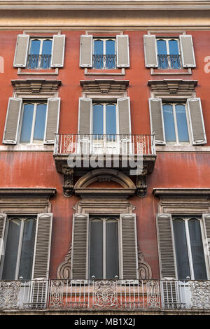 Suchen, um sich an die Wände und Fenster eines alten Mietshaus in Rom, Italien. Tief rot in der Farbe, mit der Patina der Stadt leben gut überstanden. Stockfoto