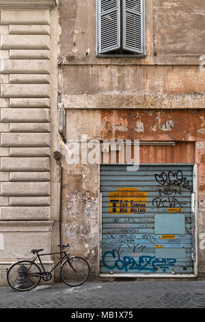 Ein altes Fahrrad an die Wand gelehnt eines Graffiti bedeckt Shutter, wo ein Self Service "Tabacchi" (TRAFIK) Einmal war, eine Szene aus der Rückseite stree Stockfoto