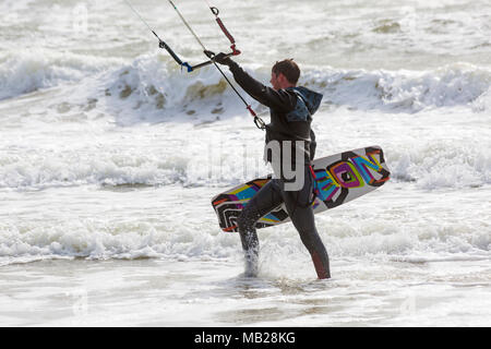 Sandbanks, Poole, Dorset, Großbritannien. April 2018. UK Wetter: Luftiger Tag in Sandbanks, wenn Kitesurfer das Beste aus den windigen Bedingungen machen. Kitesurfer mit Kiteboard geht ins Meer. Kitesurfer Kitesurfer Kitesurfer Kitesurfer Kitesurfer Kitesurfer Kitesurfer Kitesurfen Kitesurfen Kitesurfen Kitesurfen Kitesurfen Kitesurfen Kitesurfen Kitesurfen Kitesurfer Kitesurfer Kitesurfer Kitesurfer Stockfoto