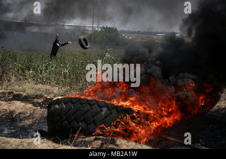 (180406) - GAZA, April 6, 2018 (Xinhua) - einen palästinensischen Demonstrant verbrennt Reifen bei Auseinandersetzungen auf der Gaza-Israel Grenze, östlich von Gaza-stadt am 6. April 2018. Hunderte von palästinensischen Demonstranten begann Freitag Feuer zu Dutzenden von Autoreifen in der Nähe der Grenze zwischen dem Osten Gazastreifen und Israel ein Schild des schwarzen Rauch zu machen, sich von israelischen Soldaten Schüsse zu schützen. (Xinhua/Stringer) (ZF) Stockfoto