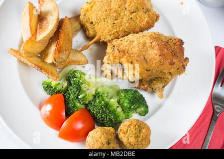 Ein englisches Pub/Restaurant Teller Golden gebratene panierte Hühnerkeule mit Kartoffelecken serviert, Brokkoli und Füllung Kugeln Stockfoto