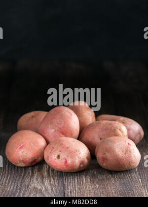 Rohe ganze Bio Kartoffeln auf alten, braunen Holz- Hintergrund. Kopieren Sie Platz. Low Key. Stockfoto