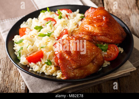 Teil der gebratenen Hühnerkeule mit Garnierung von Reis mit Gemüse auf einem Teller close-up. Horizontale Stockfoto