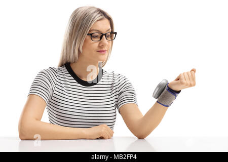 Junge Frau an einem Tisch sitzen und ihr Blutdruck auf weißem Hintergrund messen Stockfoto