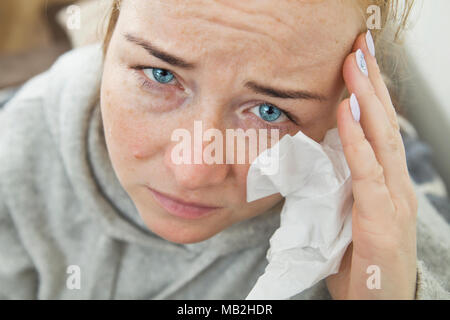 Kranke Frau mit Kopfschmerzen sitzt auf einem Sofa. Closeup Portrait. Stockfoto