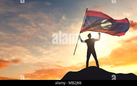 Laos Flagge geschwenkt werden von einem Mann Erfolg feiern auf der Spitze eines Berges. 3D-Rendering Stockfoto