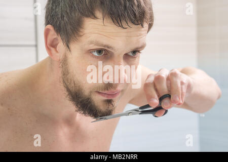 Der Kerl ist eine Schere mit Bart am Kinn Stockfoto