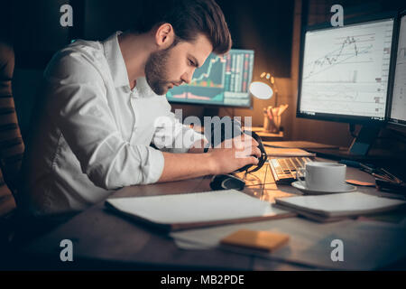 Junger bärtiger Mann Händler im Büro am Tisch halten virtual reality Headset sitzen auf der Suche konzentriert Stockfoto