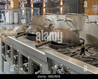 Zwei woks bereit, beleuchtete industrielle Küche zu kochen Stockfoto