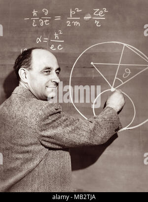 Enrico Fermi (1901-1954), italienisch-amerikanische Physiker und Pionier der Kernspaltung, zeigt eine Physik Gleichung auf einer Schiefertafel, c 1950. Fermi arbeitete auf dem Manhattan Projekt während des Zweiten Weltkrieges und wichtige Beiträge für die Entwicklung der Quantentheorie, Kern- und Teilchenphysik und Statistische Mechanik. Stockfoto