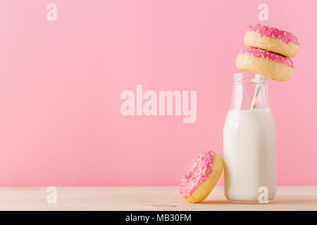 Glas Flasche Milch und süß lecker Rosa glasierten Krapfen auf rosa Hintergrund. Stockfoto