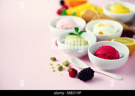 Rot, violett, gelb, grün, weiß Eis Kugeln in Schalen, Waffeln, Beeren, Orange, Mango, Zitrone, Minze, Pistazie, Rosa shabby chic Hintergrund. Stockfoto