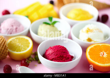 Rot, violett, gelb, grün, weiß Eis Kugeln in Schalen, Waffeln, Beeren, Orange, Mango, Zitrone, Minze, Pistazie, Rosa shabby chic Hintergrund. Stockfoto