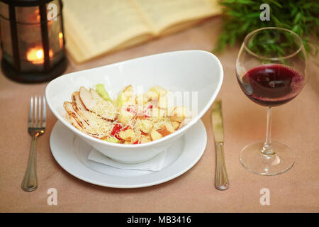 Frische Caesar Salat auf große Platte mit gegrilltem Hähnchenbrustfilet und Wein Glas Stockfoto