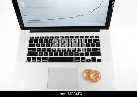 Zwei goldene Bitcoins auf Silber Laptop mit finanziellen Plan auf dem Bildschirm platziert. Cryptocurrency virtuelle digitale Geld web elektronische Währung blockchain zukünftige Trends innovative Business Mining Exchange Stockfoto