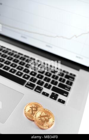 Zwei goldene Bitcoins auf Silber Laptop mit finanziellen Plan auf dem Bildschirm platziert. Cryptocurrency virtuelle digitale Geld web elektronische Währung blockchain zukünftige Trends innovative Business Mining Exchange Stockfoto