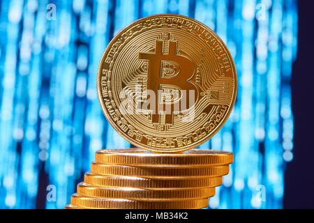 Eine bitcoin auf die Kante des Stapels von Golden bitcoins mit unscharfen Blau im Hintergrund. Digitale virtuelle Geld elektronische Währung blockchain Börse Zukunft innovative Banking Stockfoto
