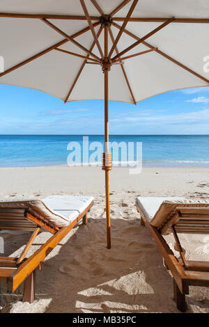 Sonnenliegen und Sonnenschirme am tropischen Strand Stockfoto