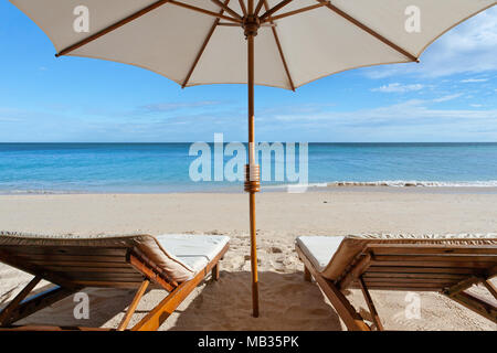 Sonnenliegen und Sonnenschirme am tropischen Strand Stockfoto