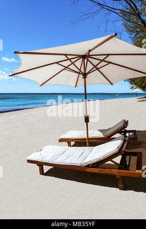 Sonnenliegen und Sonnenschirme am tropischen Strand Stockfoto