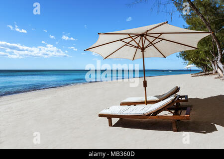 Sonnenliegen und Sonnenschirme am tropischen Strand Stockfoto