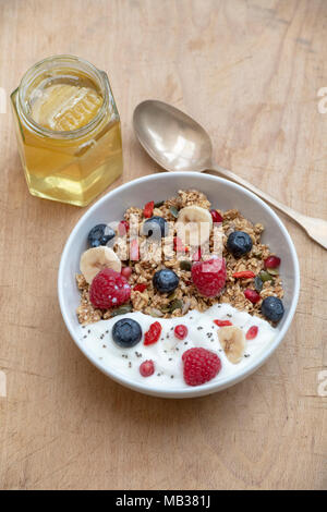 Frühstück Schüssel Müsli, Früchte, Samen, Joghurt und Honig auf einem Holz Hintergrund Stockfoto