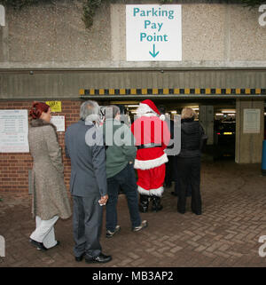 Ein lustiges Bild von Santa Claus (Weihnachtsmann) wartet inline für einen Parkplatz bezahlen Punkt in einem mehrstöckigen Parkhaus. Stockfoto