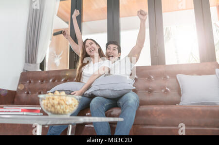 Asiatische paar Fernsehen auf der Couch zu Hause sitzen Stockfoto