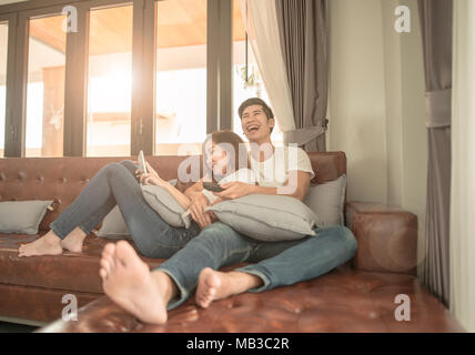 Asiatische paar Fernsehen sitzen auf einer Couch zu Hause heiter Stockfoto