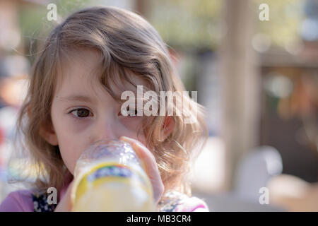 Junge Mädchen trinken lemon Fanta direkt aus der Flasche an einem sonnigen Tag Stockfoto