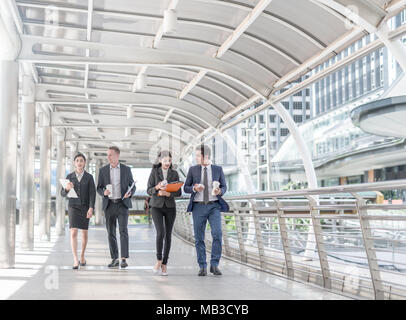 Gerne Kollegen zu Fuß außerhalb Büro & miteinander zu reden. Unternehmer gehen sprechen und halten Kaffee Tasse Stockfoto
