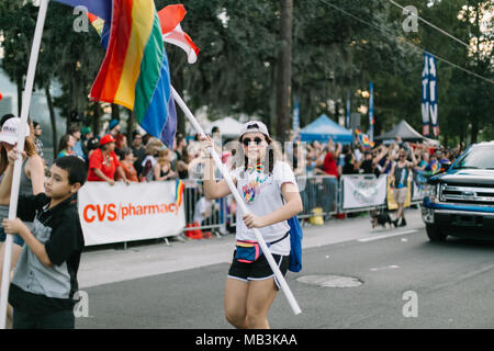 Person mit „Make American Gay Again“-T-Shirt und Regenbogenfahne bei der Orlando Pride Parade (2016). Stockfoto