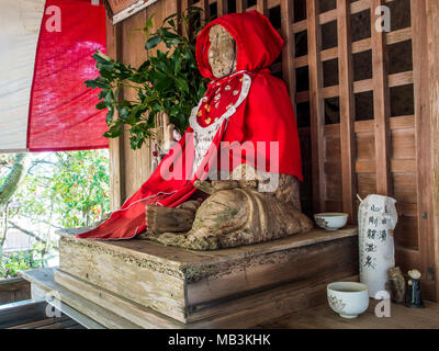 Binzuru Sonja, japanischen Gott der Heilkunst, hölzerne Statue, alt und abgenutzt, in roten Roben gekleidet, bei Butsumokuji, Tempel 42 der 88 Tempel Shikoku Pilgerweg Stockfoto