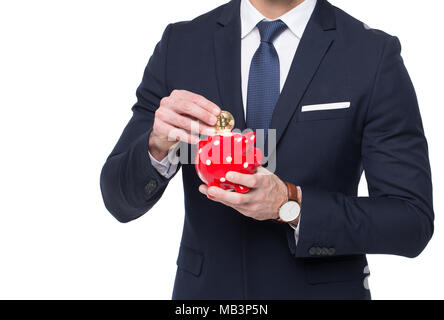 Geschäftsmann drop golden Bitcoin in Sparschwein isoliert auf weißem Stockfoto