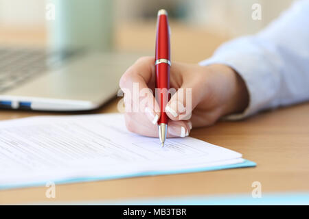 Nahaufnahme eines Geschäftsfrau Hand unterzeichnen einen Vertrag auf dem Schreibtisch im Büro Stockfoto