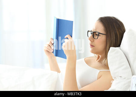 Müde Frau mit einem Buch Tragen von Brillen auf dem Bett zu Hause. Stockfoto