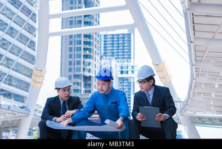 Ingenieure treffen auf der Terrasse auf der Baustelle. Mitarbeiter diskutieren. Chef und Arbeitnehmer streiten. Gespräch in Team. tragen Helm halten Papier pla Stockfoto