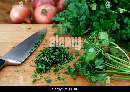 Frisch zerkleinert Bund Petersilie auf Holz Schneidebrett neben Küche Messer. Stockfoto