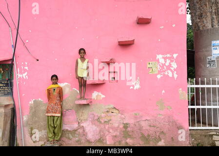 Indische Kinder gegen eine rosa Wand in Abhaneri, Rajasthan, Indien posieren. Stockfoto