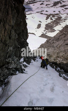 Männliche Bergsteiger in einer sehr steilen und schmalen Gully auf einem Seil und Suchen nach unten Stockfoto