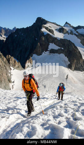 Bergführer und client Position auf einem Gletscher in Richtung einer hochalpinen Gipfel an einem schönen Sommermorgen Stockfoto