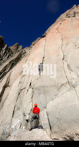 Zwei Kletterer auf einem schwierigen Weg in eine vertikale Granitwand in den Französischen Alpen unter einem blauen Himmel Stockfoto