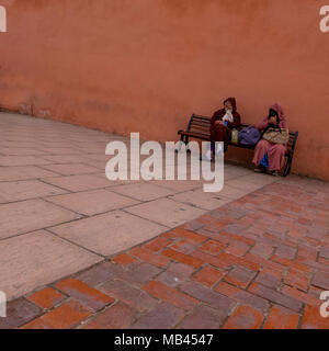 Zwei Leute saßen auf einer Bank an der Moschee Koutoubia, Marrakesch, Marokko Stockfoto