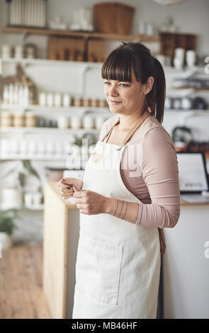 Junge weibliche Florist lächelnd während sie arbeitet allein in ihrem Blumenladen Stockfoto