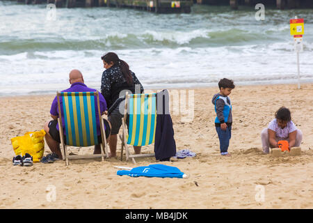 Bournemouth, Dorset, Großbritannien. 7. April 2018. UK Wetter: Nach einem feuchten Start in den Tag die Sonne versucht, heraus zu kommen, obwohl es auf der kühlen Seite Besucher gehen nach Bournemouth Strand am Meer während der Osterferien zu genießen. Stockfoto