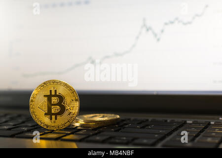 Bitcoin cryptocurrency Münze, stehend auf einem Laptop Tastatur mit aufsteigender Diagramm auf verschwommenen Hintergrund Stockfoto