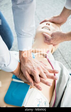 Ersthelfer üben HLW Training dummy. Automatisierter externer Defibrillator Pads haben auf der Prüfpuppe Brust platziert worden. Stockfoto