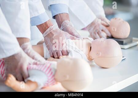 Ärzte üben die Herzdruckmassage auf ein Kleinkind HLW Training dummy. Stockfoto